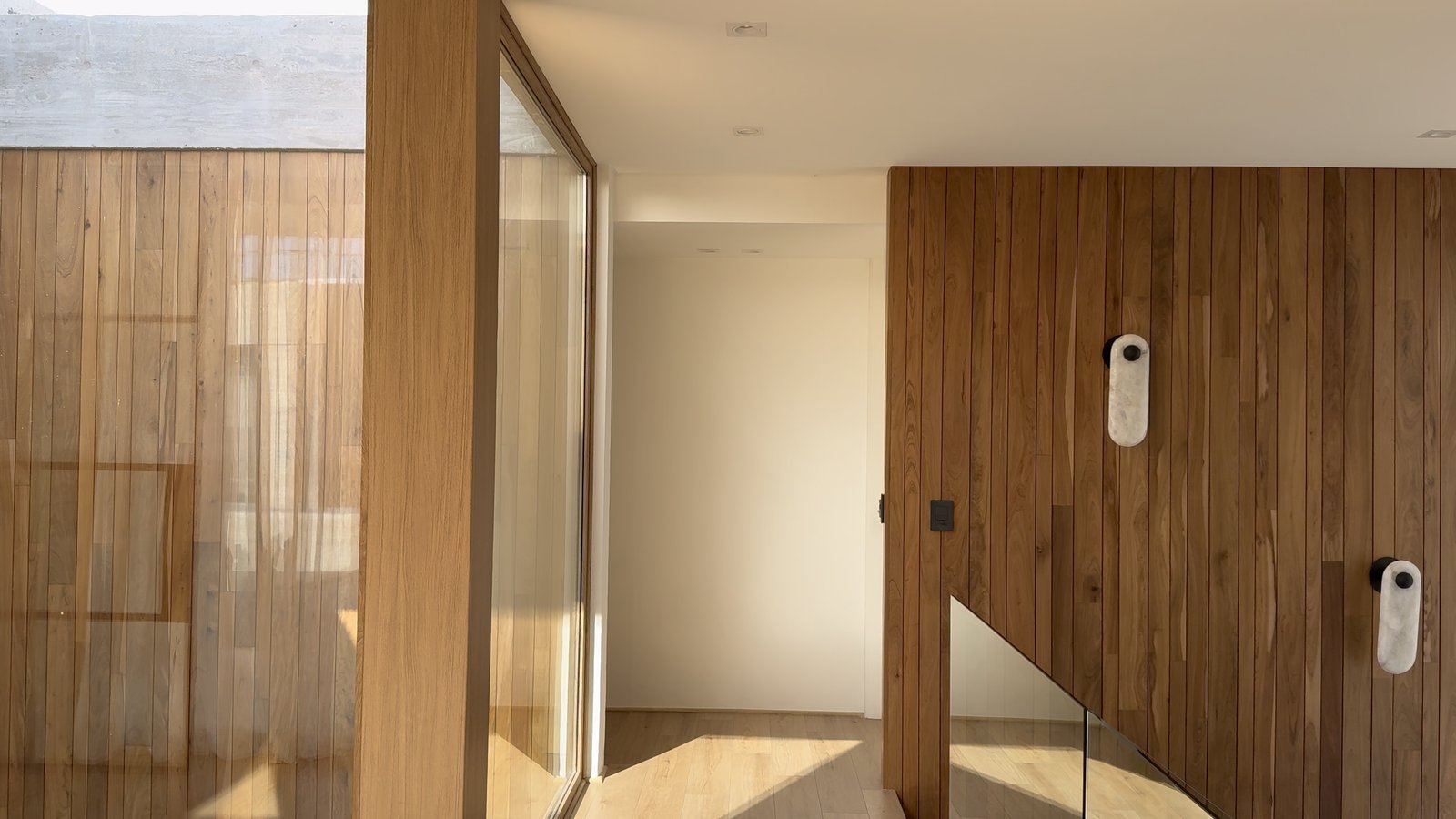 Corredor moderno com escadas e painéis de madeira — projeto CASA MHN, por Hermann Arquitectos, em Nordelta